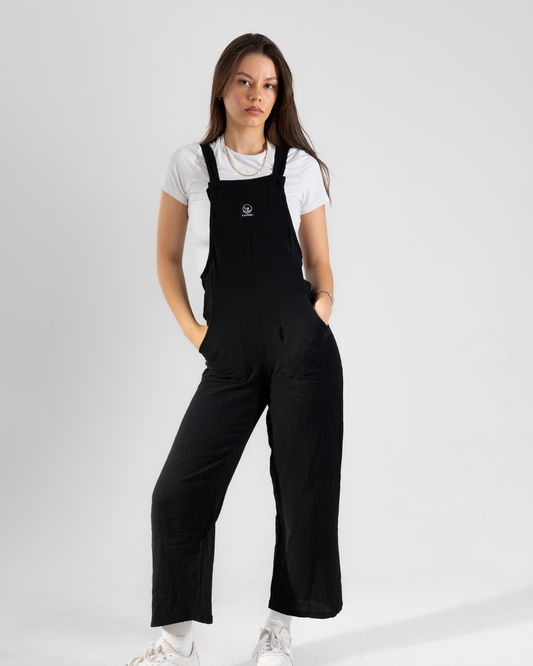 Female wearing a white shirt with black cotton dungarees over it.