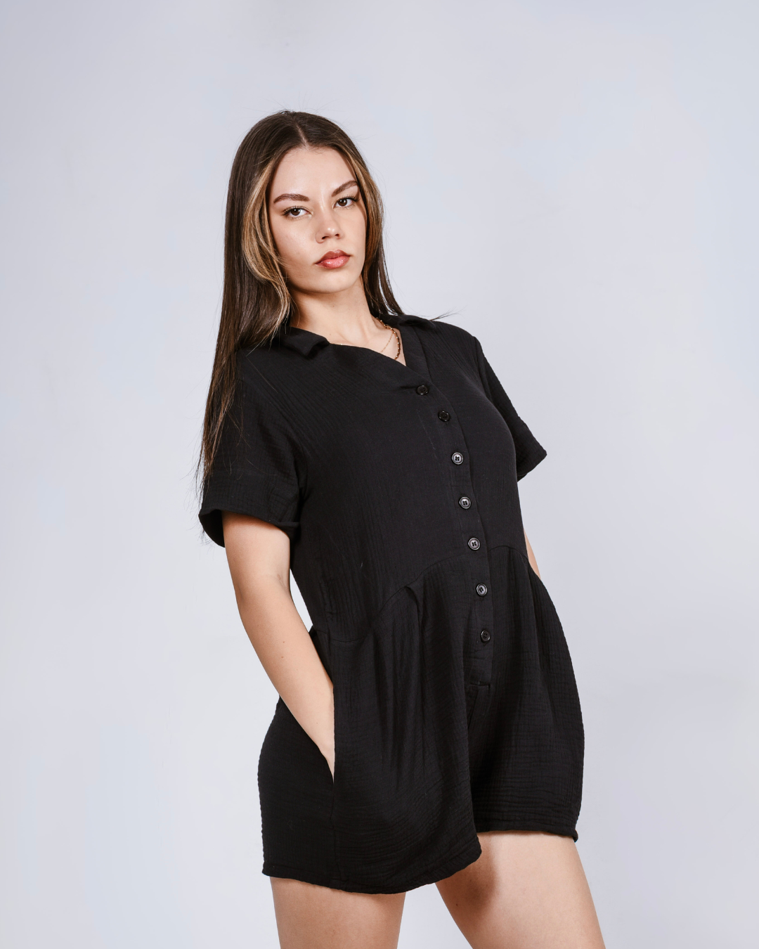Woman wearing a black button up romper with pockets.