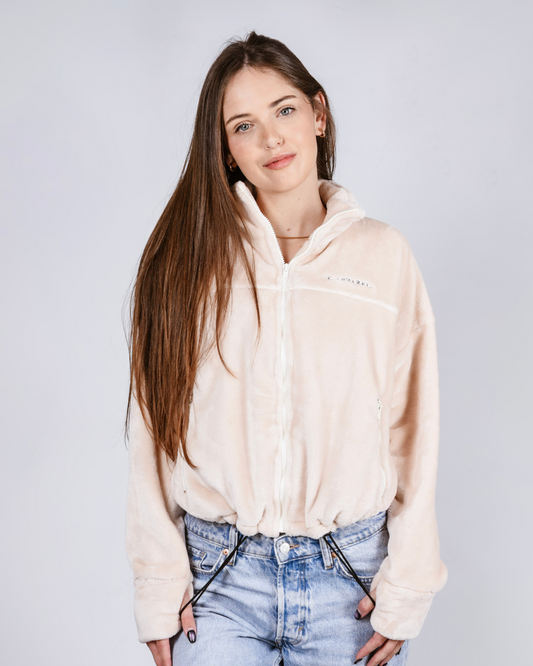 woman wearing a cream fluffy zip up jacket with draw cords and thumb holes