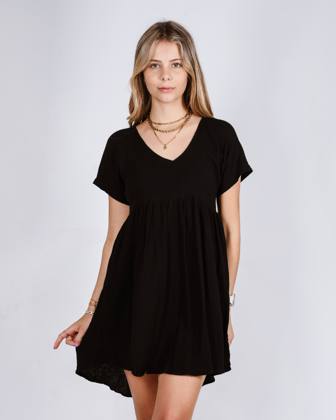 Woman wearing a black cotton dress against a plain background