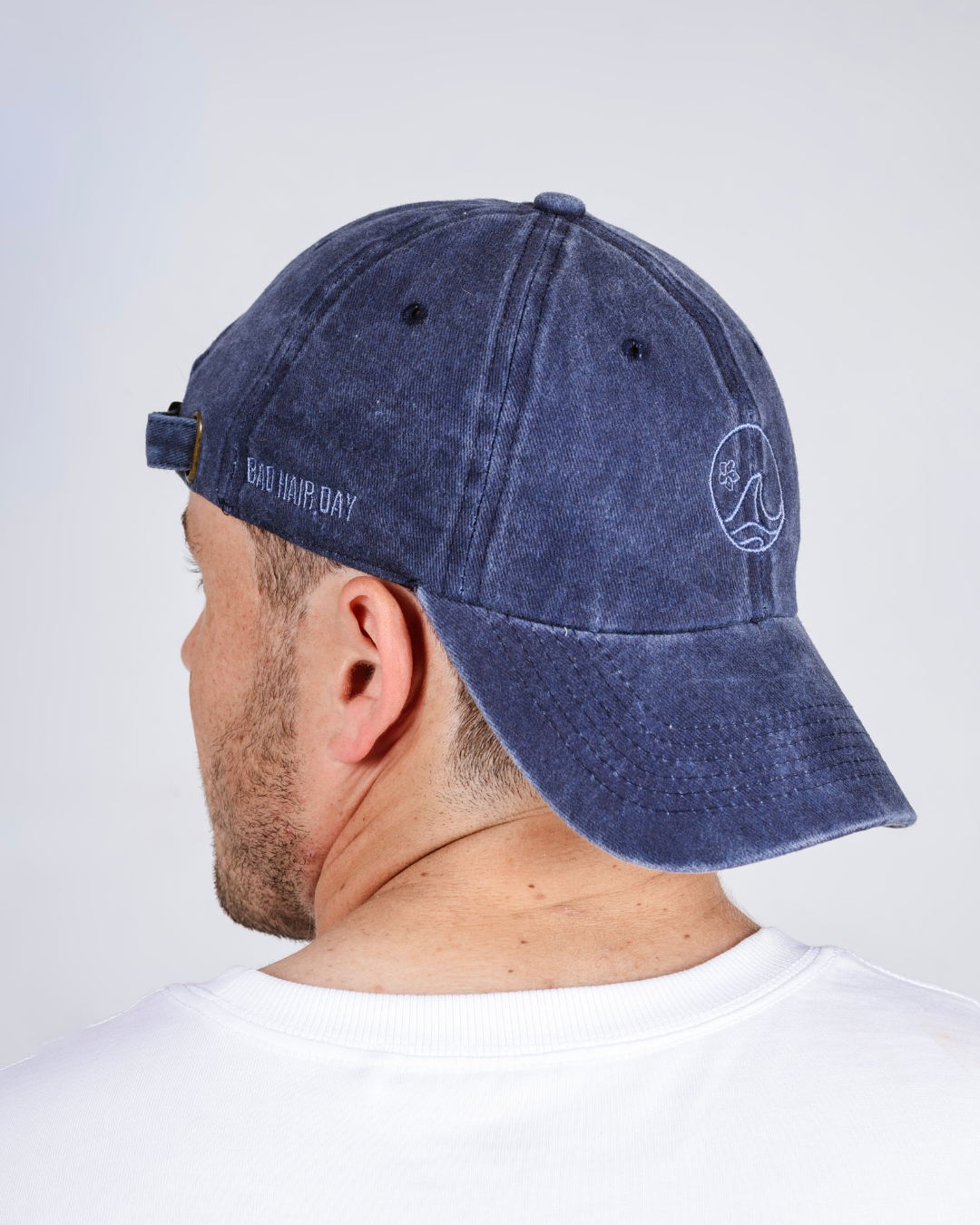 Navy blue cap worn by a person on a light gray background
