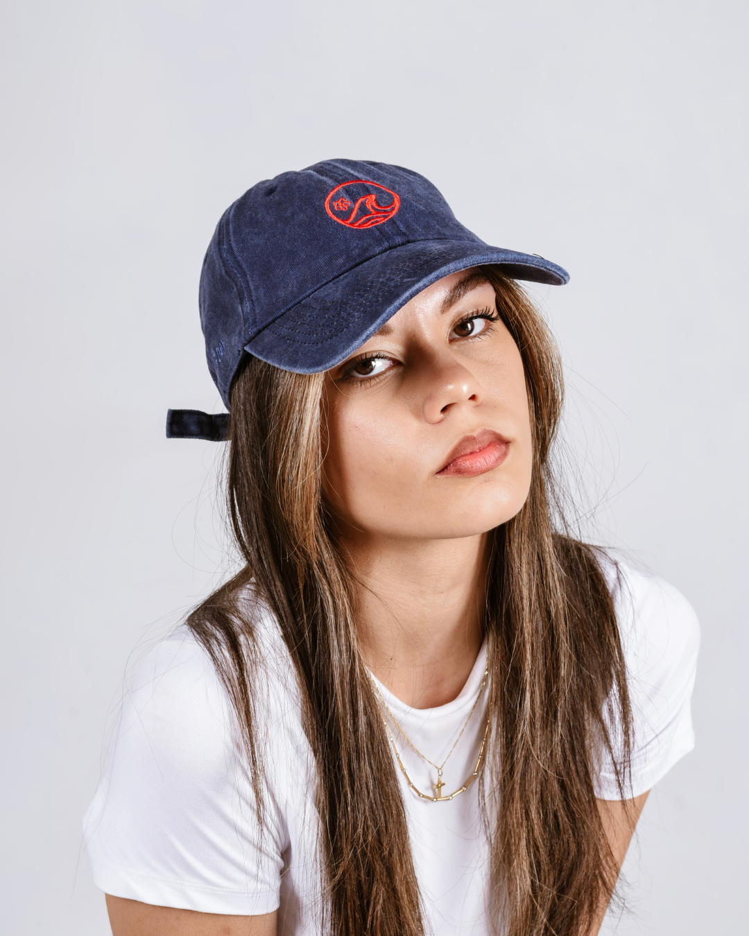 Woman wearing a blue cap with a red logo on a light gray background