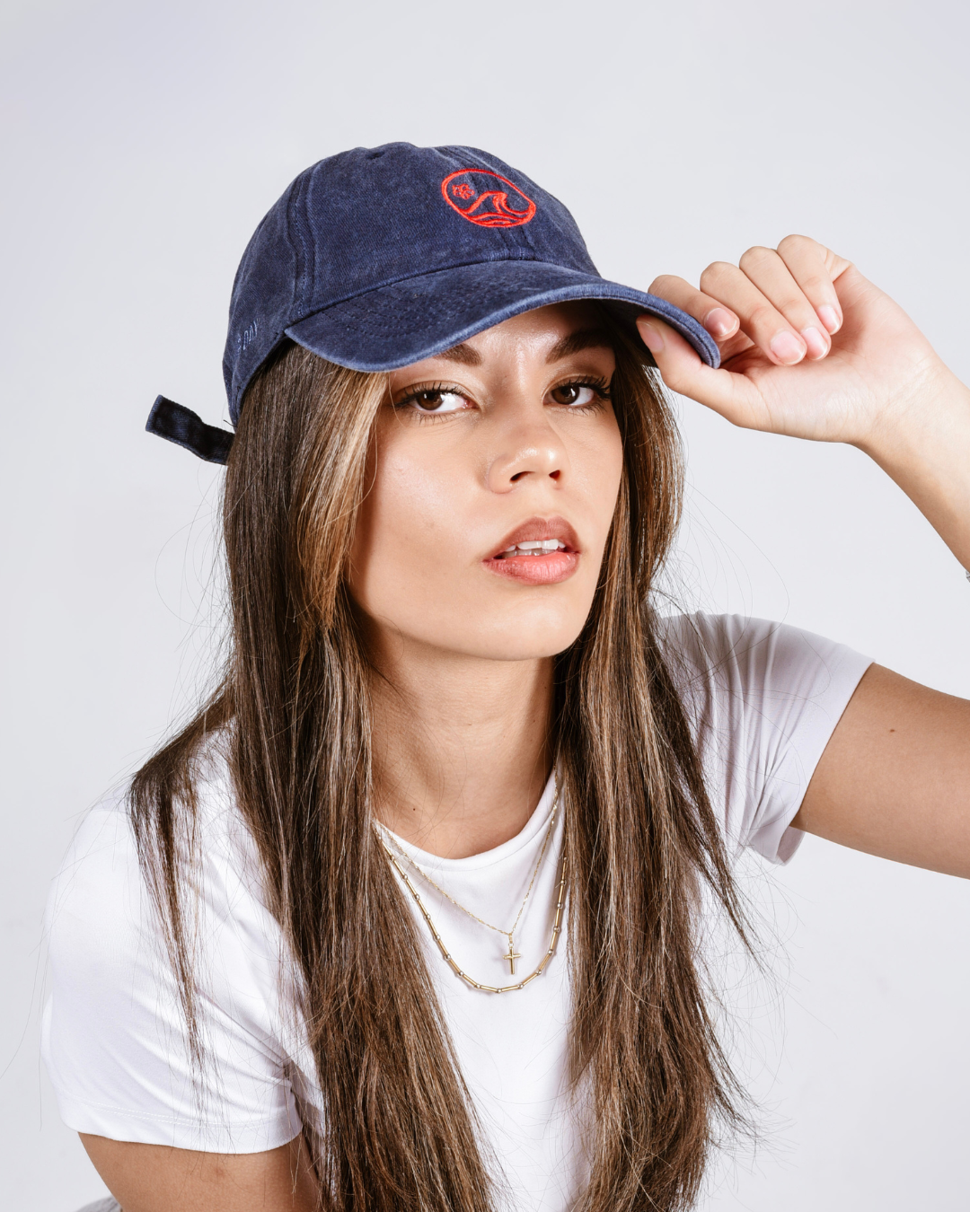 Woman wearing a blue cap with a red logo on a white background