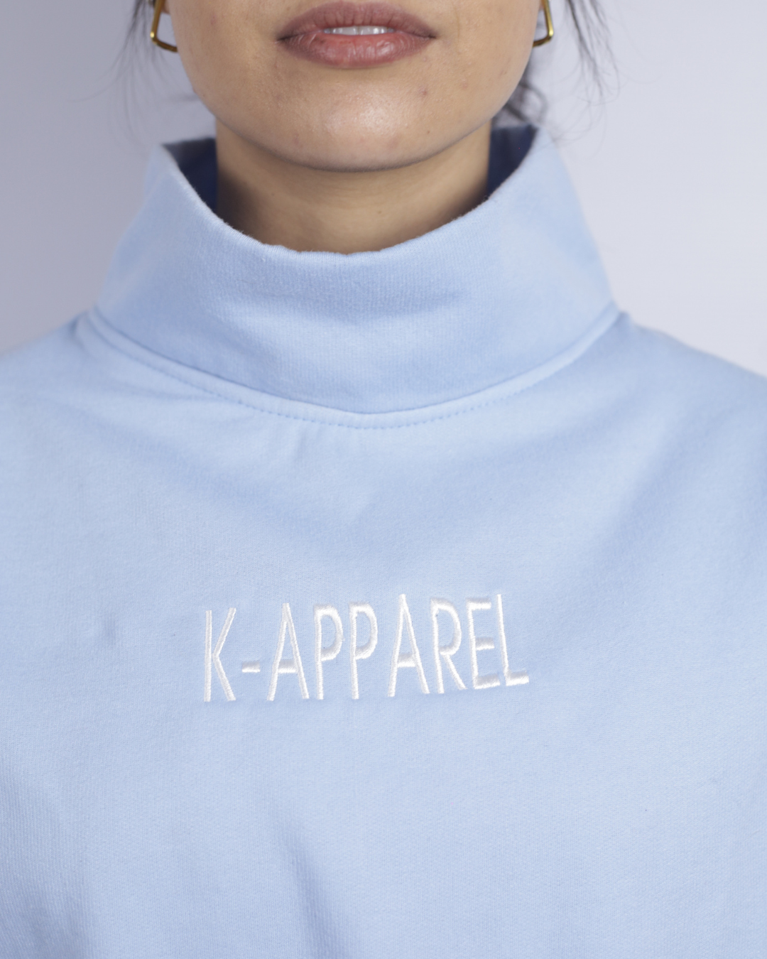 Light blue sweatshirt with 'K-Apparel' text worn by a person