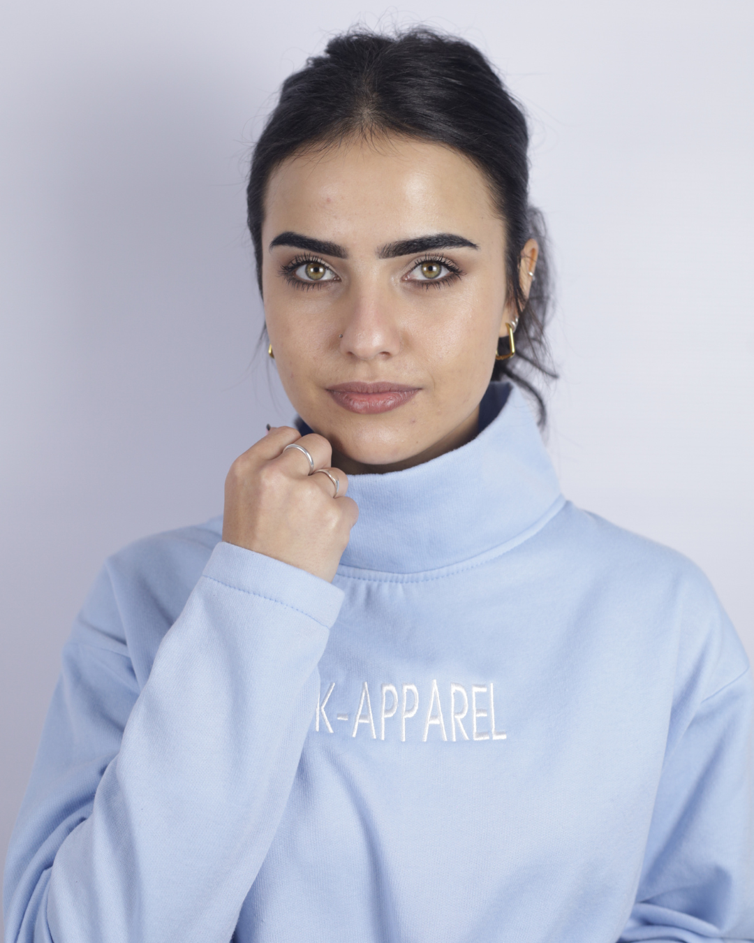Person wearing a light blue turtleneck with 'K-Apparel' branding on a plain background