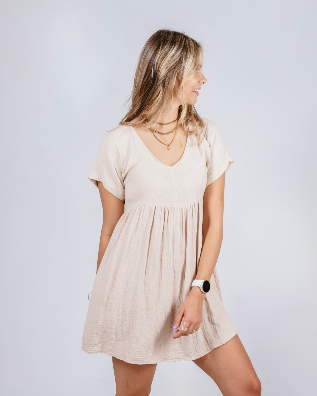 Woman wearing a beige / cream cotton dress against a white background