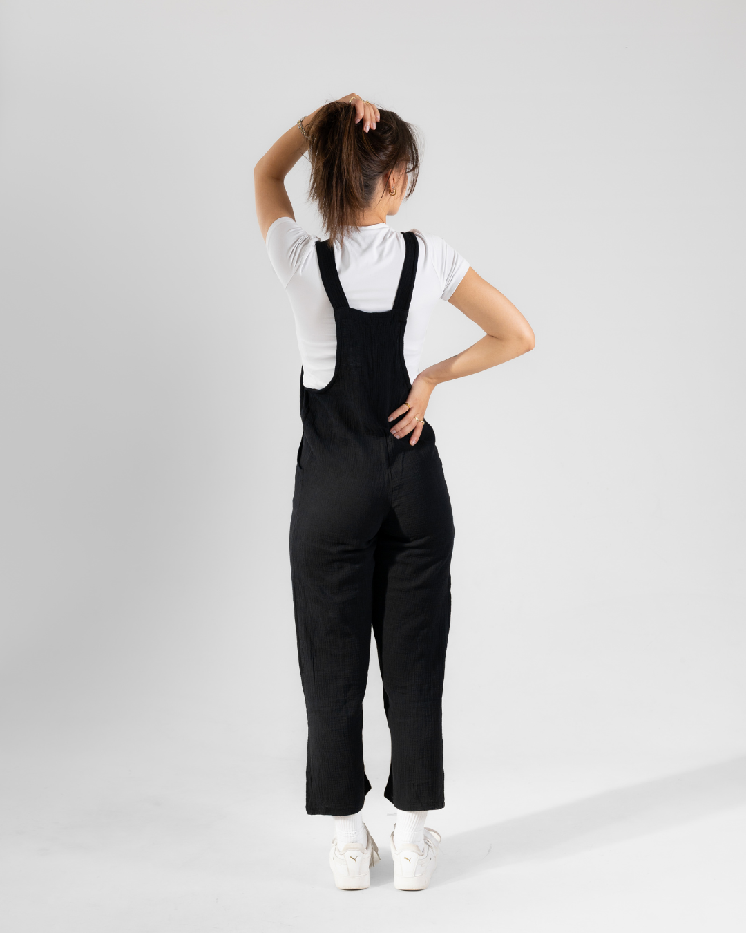 Back view of female wearing a black cotton dungaree 