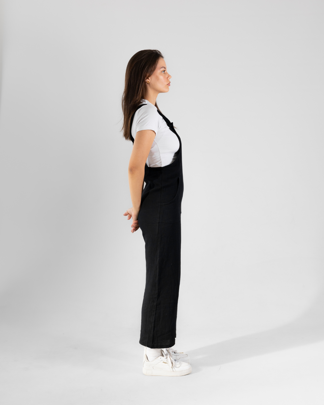 Side view of a female wearing a black coton dungaree
