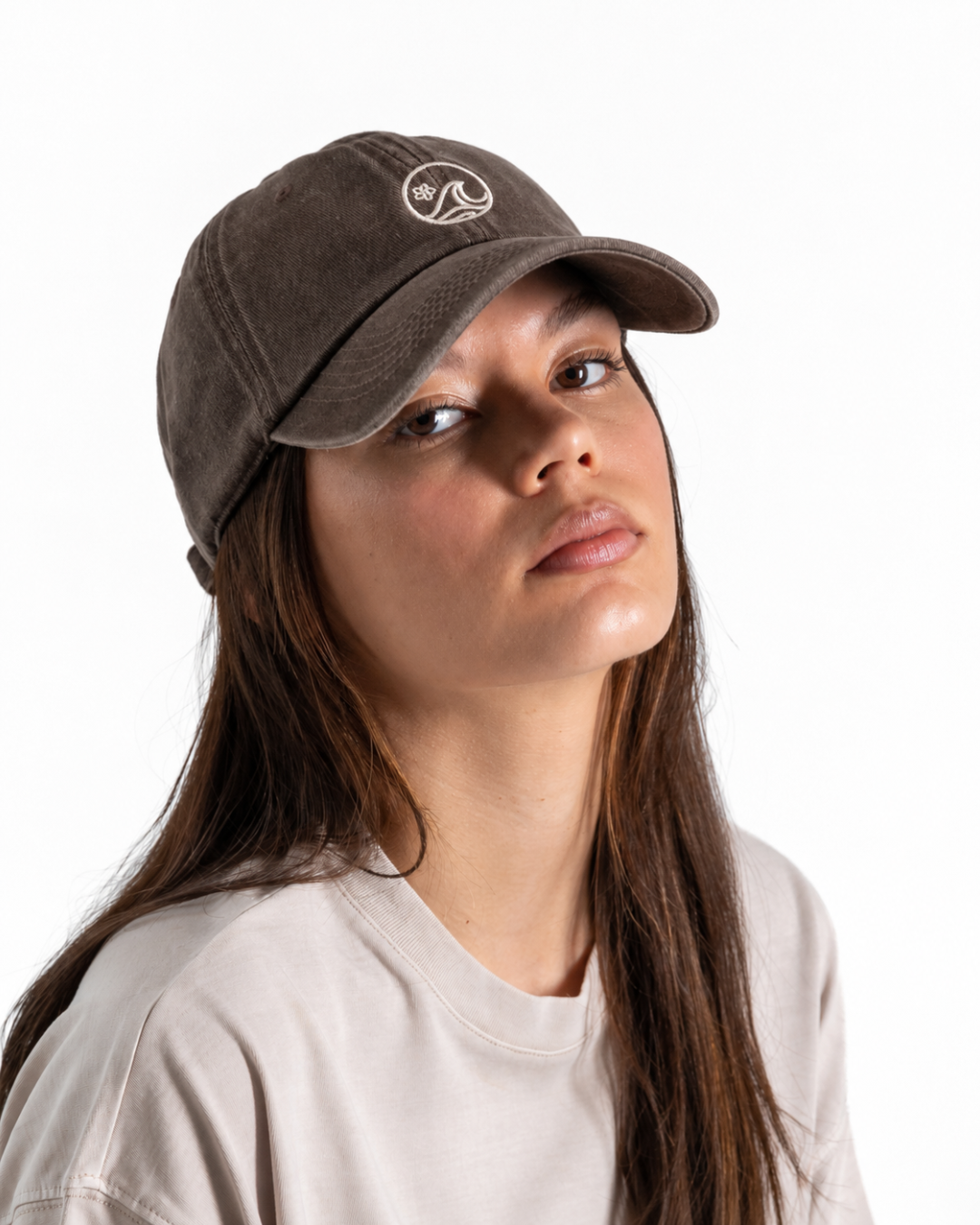 Female wearing a brown cap with a white logo on the front 