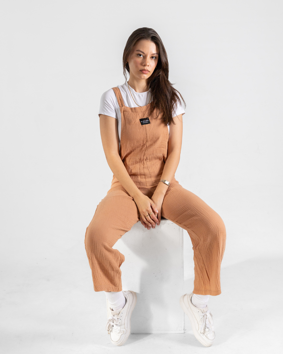 Female wearing a coral cotton dungaree in studio