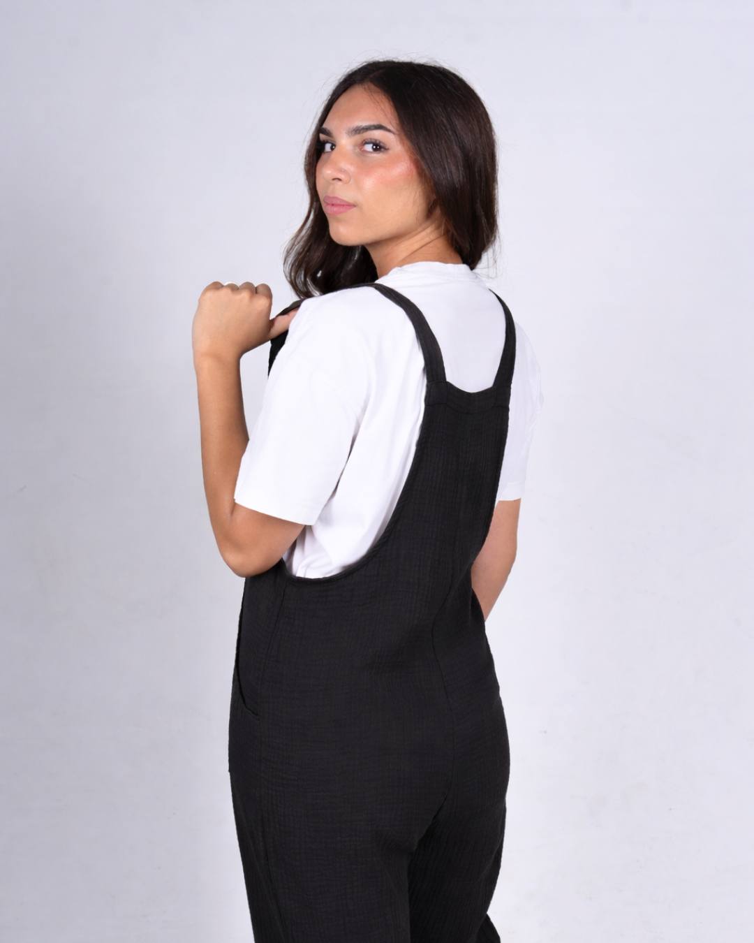 Female wearing black cotton dungarees side view