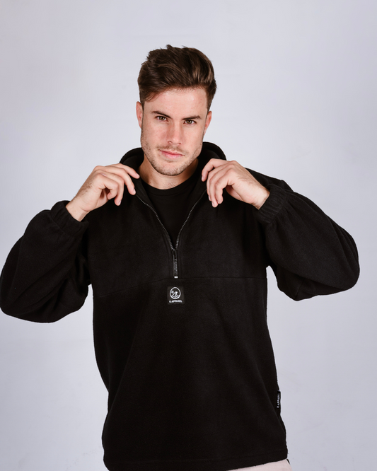 Man wearing a black quarter zip fleece pullover with a brand logo on a light gray background