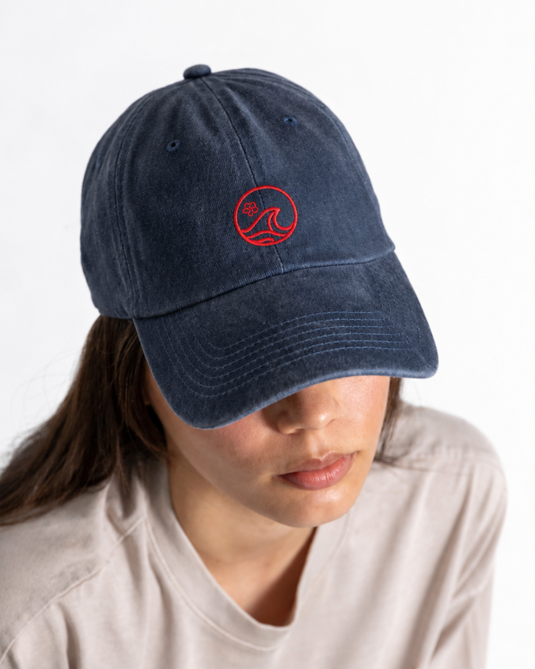 Female wearing a navy cap with a red logo on the front 