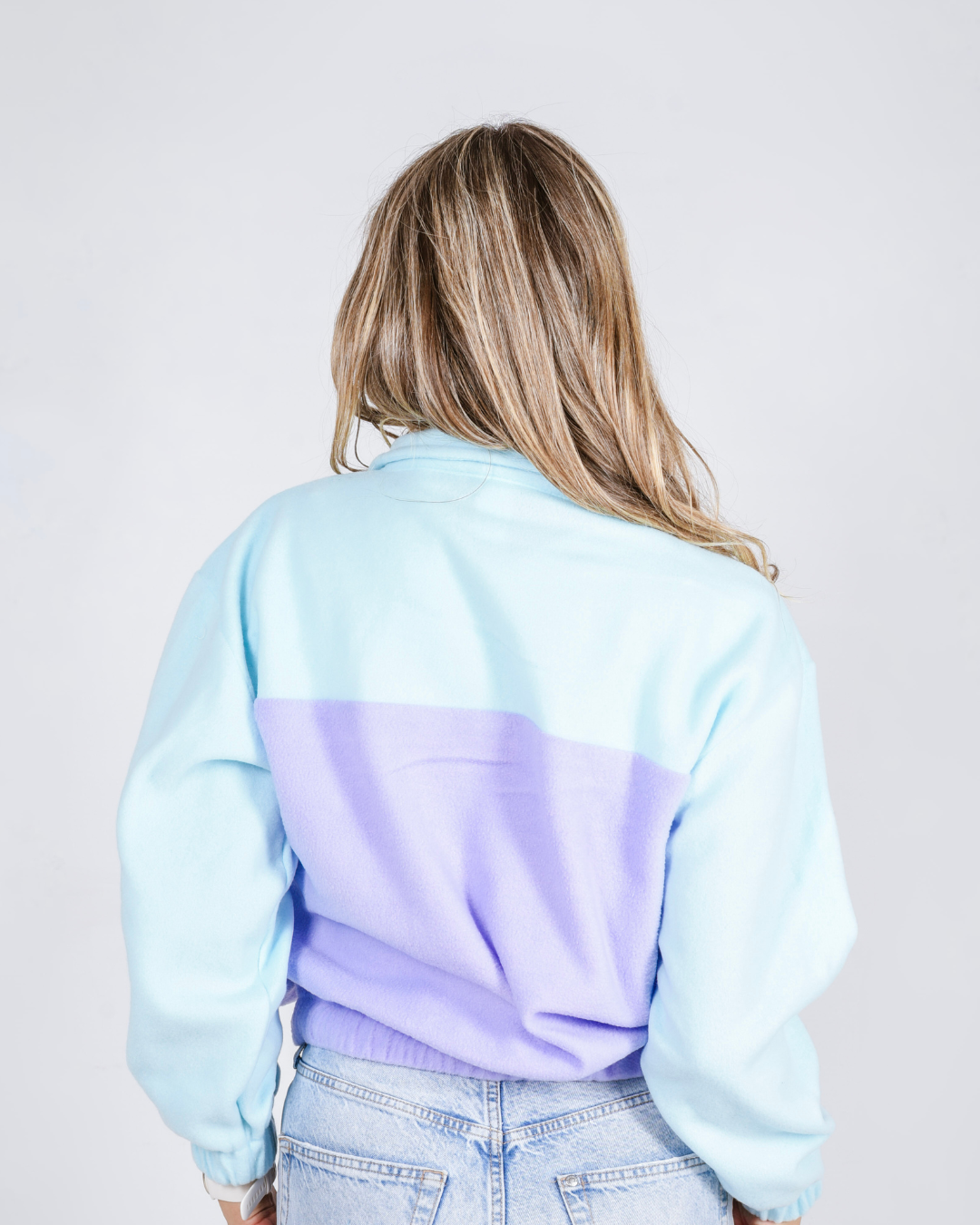 Female wearing an OG quarter zip retro jersey in the colour purple and teal. 