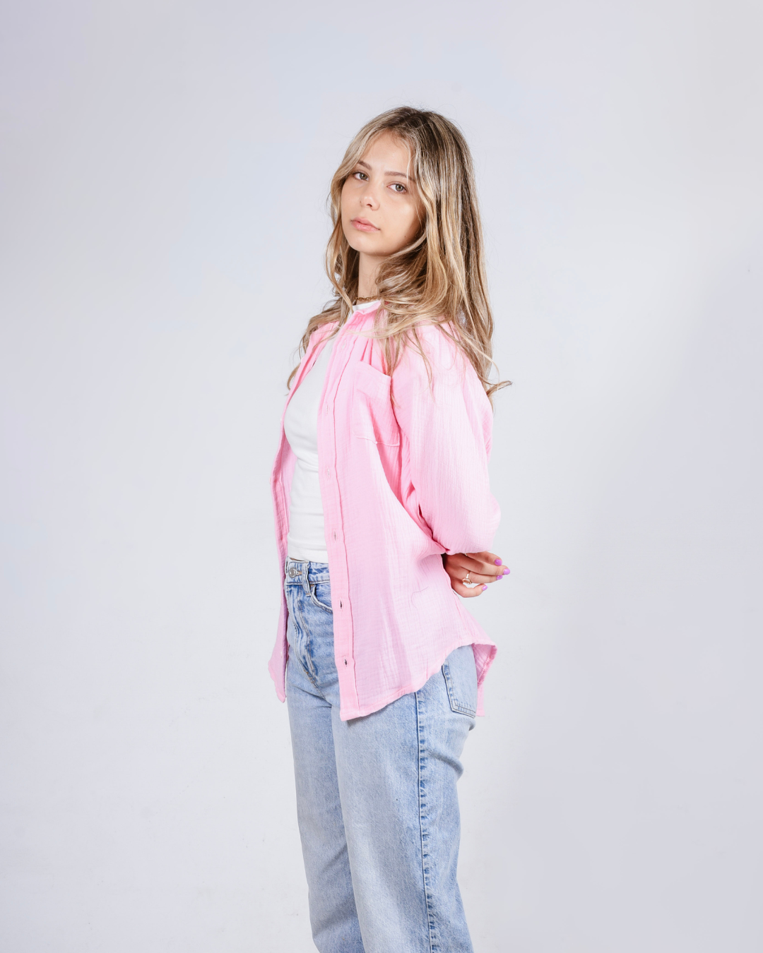 Female wearing a pink button up cotton shirt - side view